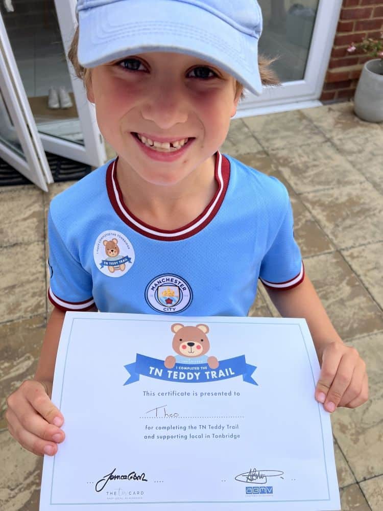 Theo holds the teddy trail certificate