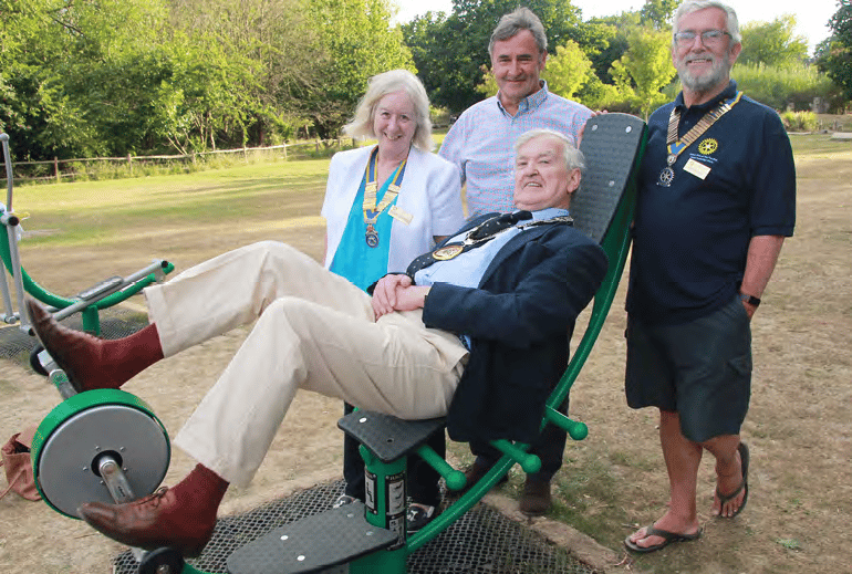 Mayor on a exercise machine with three people behind him