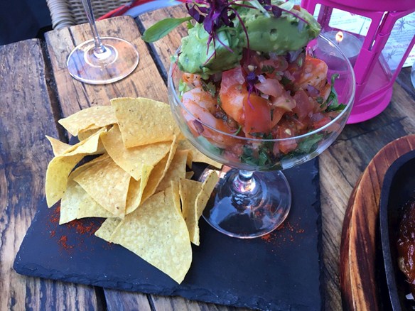 spicy king prawns served in a martini glass and topped with salad and avocado